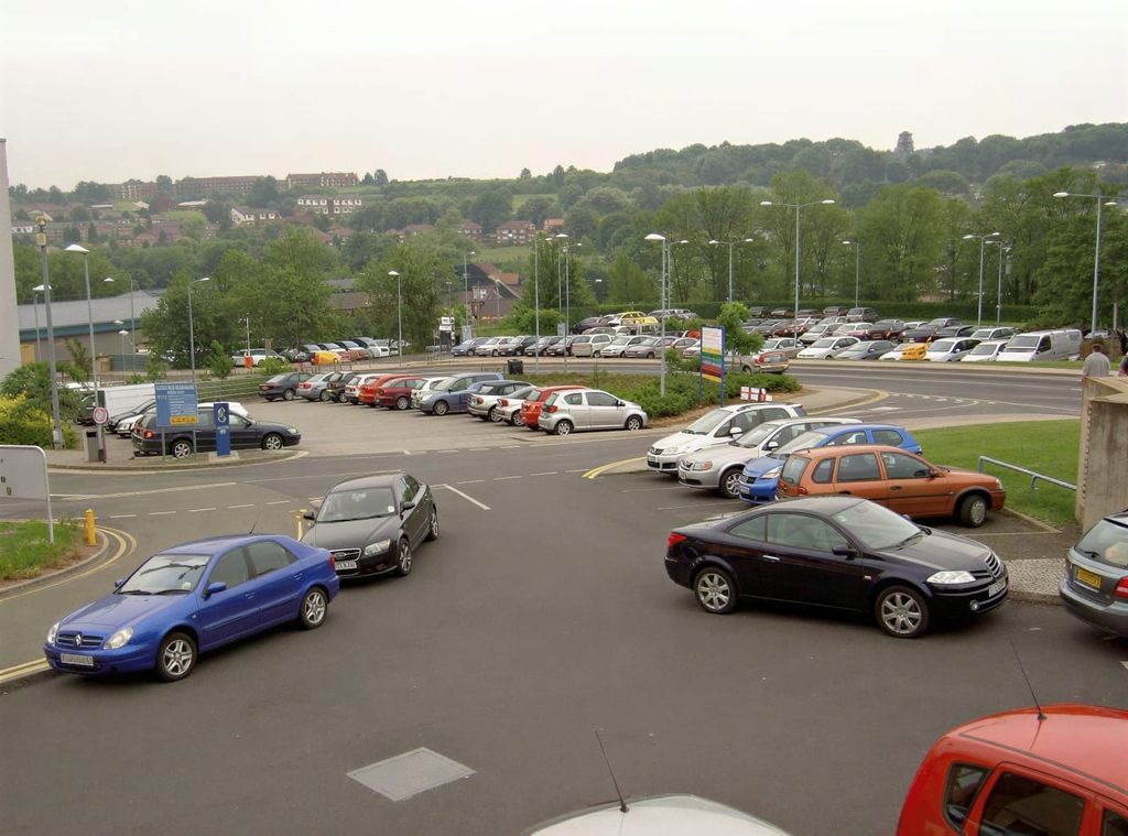 Ogrodzony parking odkryty z zaparkowanymi samochodami